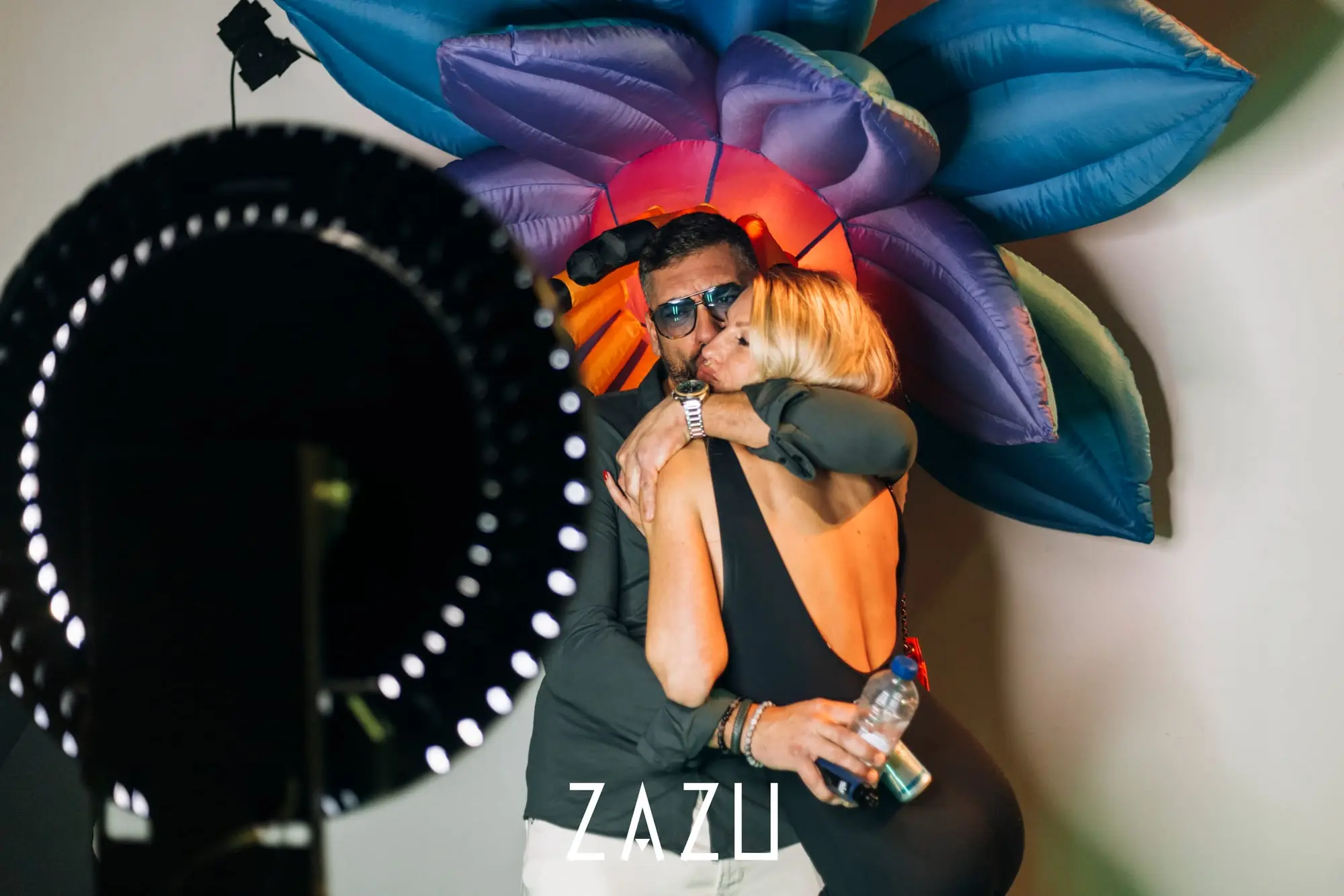 Gasten voor een opblaasbare bloeminstallatie, met de ringlamp van de fotobooth in beeld