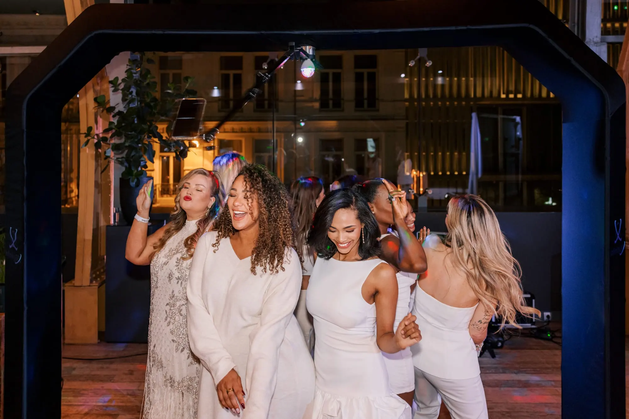 Een groep gasten in het wit op de plaat van de videobooth 2.0, onder de boog