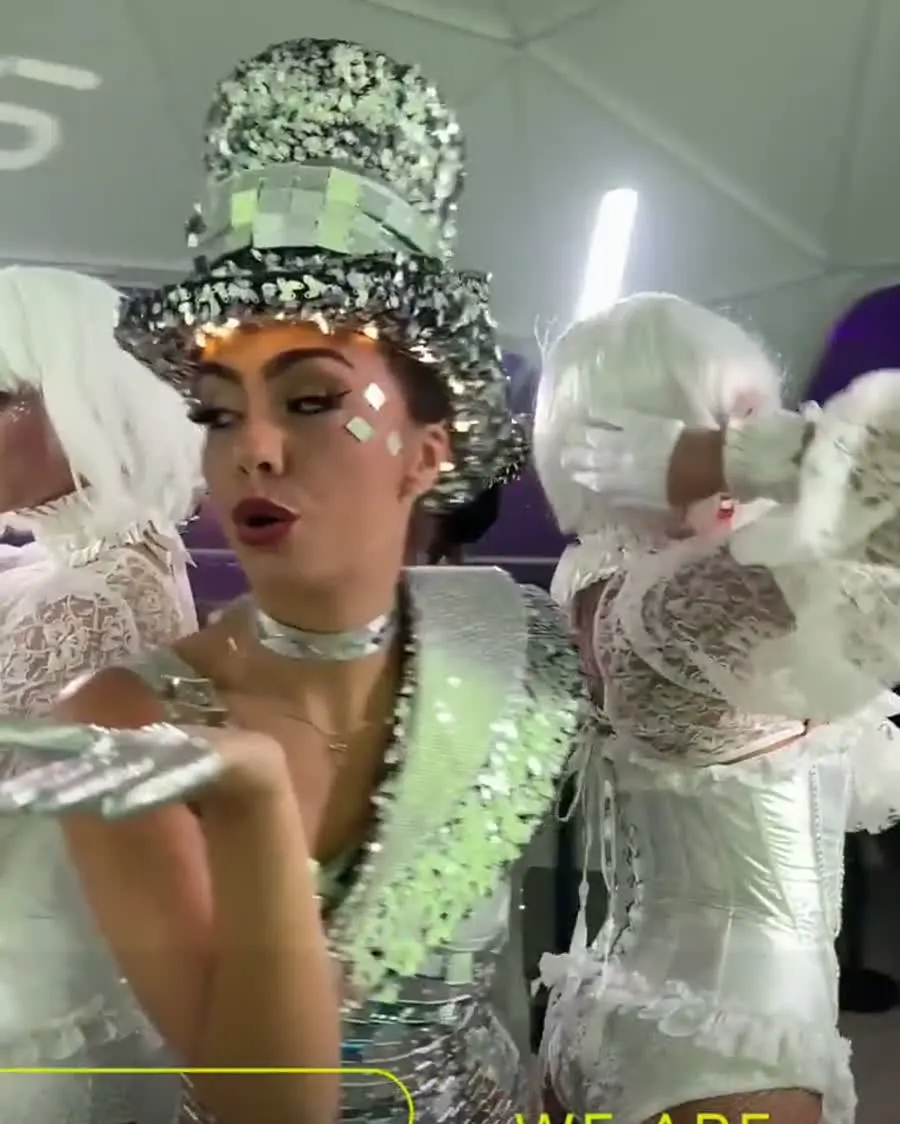 Artiesten in zilveren kostuums, een van hen met een glitterhoed, in de booth