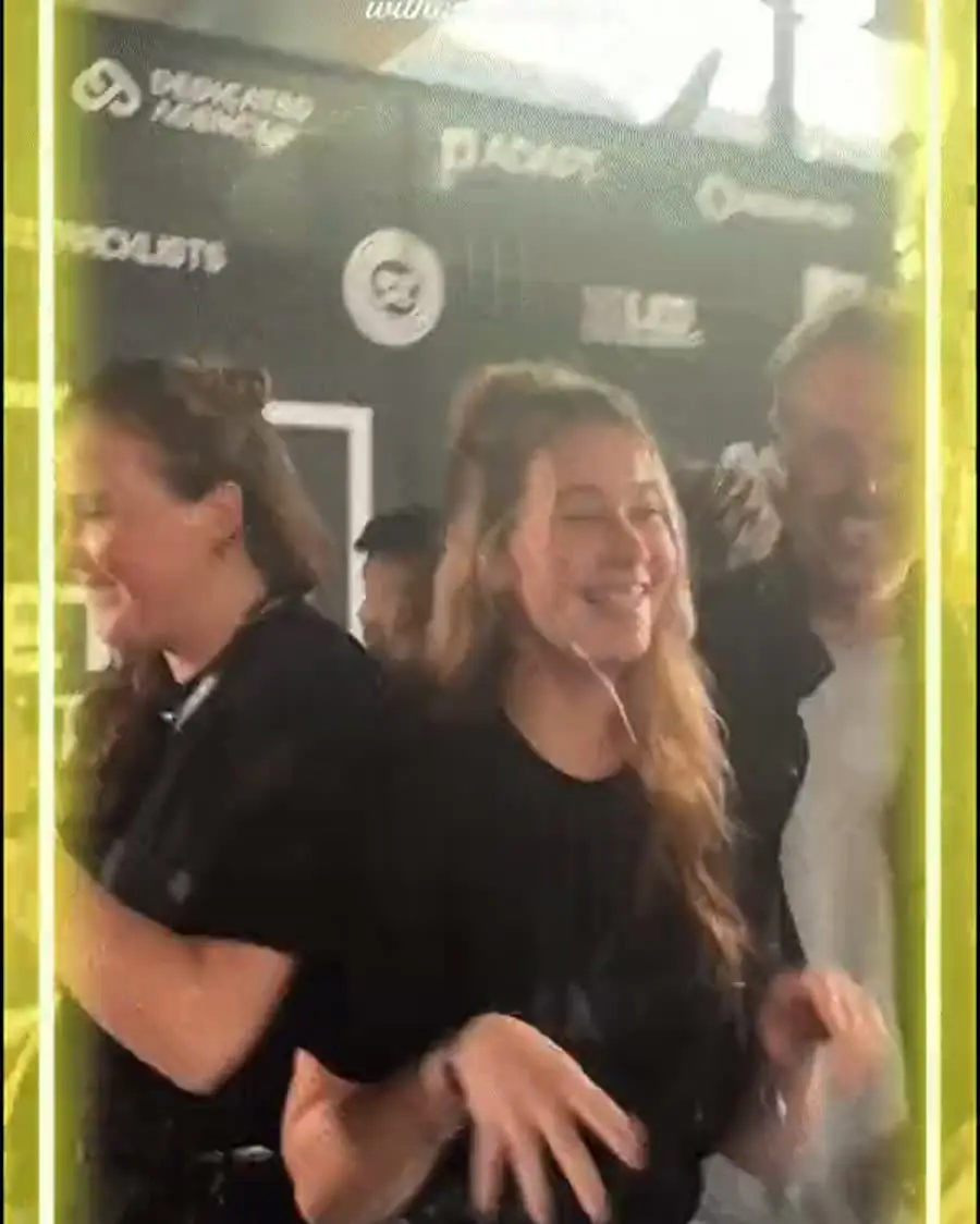 Gasten dansen in de booth, voor de perswand van een evenement