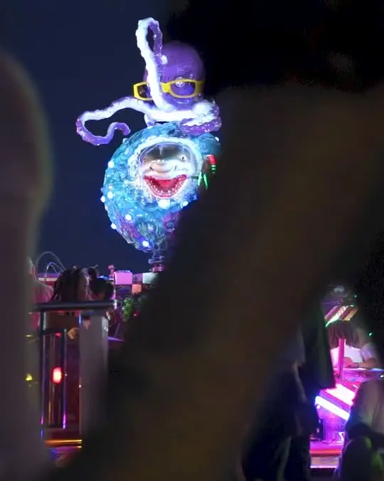 Een verlichte attractie boven een festivalterrein bij avond