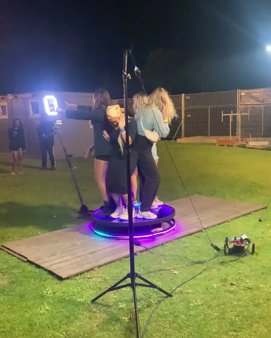Gasten op het verlichte plateau van de videobooth, ’s avonds op het gras