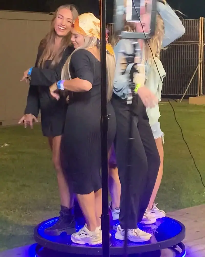 Drie gasten op het verlichte plateau van de videobooth, op een festival