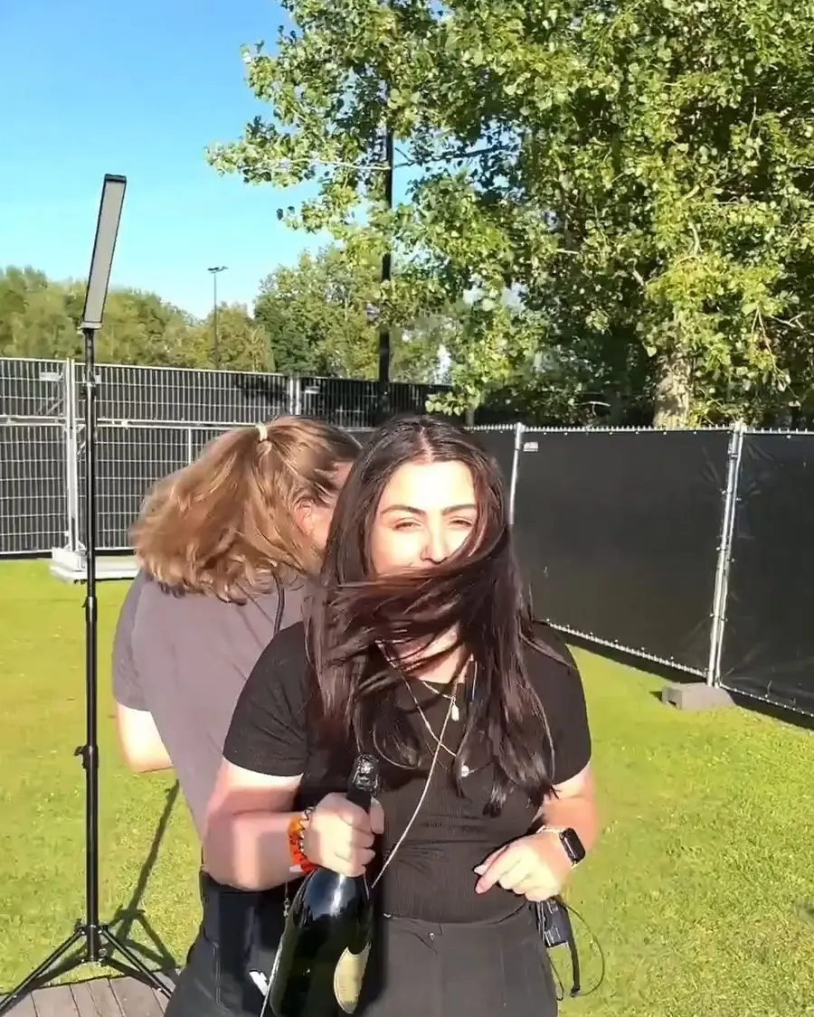 Twee gasten met een fles bubbels bij de booth op een festivalterrein