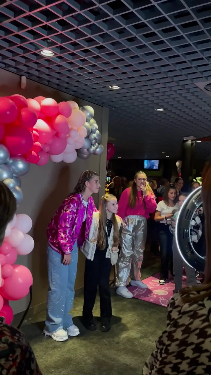 Gasten voor een roze klatergoudgordijn op een dansfeest, met een eigen naam in het frame